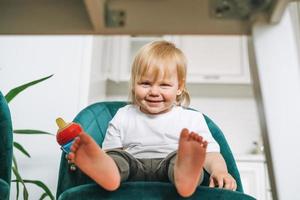 süßes lustiges kleines Mädchen im Stuhl zum Füttern in der hellen Küche zu Hause foto