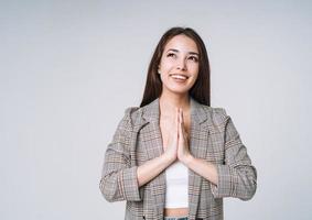 junge glückliche asiatische Frau mit langen Haaren im Anzug auf grauem Hintergrund foto