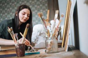 junge künstlerin teenager studentin mit dunklen langen haaren in lässigen zeichnet bild im art studio foto