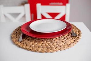 tischdekoration für einen romantischen feiertag valentinstag, rote und weiße teller mit bambusgeschirr auf weißem tisch. selektiver Fokus. foto