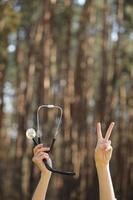 hände, die ein stethoskop halten und v-zeichen auf naturwaldhintergrund zeigen foto