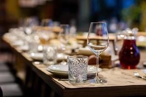 gedeckte Tische für eine Eventparty oder einen Hochzeitsempfang. luxuriöses, elegantes Abendessen in einem Restaurant. Gläser und Geschirr. leere Gläser im Restaurant. Teil des Innenraums foto