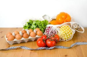 Gemüse, Obst und Eier in der Nähe von Hanteln und Maßband. Sport- und Ernährungskonzept. gesundes Essen foto