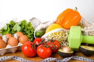 Gemüse und Obst in der Nähe von Hanteln und Maßband. Sport- und Ernährungskonzept. gesunde Essgewohnheiten foto