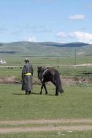 nicht erkennbarer mann mit traditioneller mongolischer kleidung, der neben seinem pferd geht foto