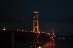 beleuchtete golden gate bridge über der bucht von san francisco bei nacht foto