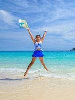 mädchen, das mit glücklichem auf dem strand in thailand springt foto