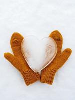 Valentinstag. Herz-Symbol der Liebe, aus Eis, auf warmen gelben Strickfäustlingen, im Schnee. romantisches Konzept. Ansicht von oben. foto