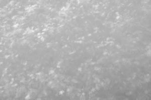 Schneeflockenkristalle leuchten in den Sonnenstrahlen auf flauschigem Schnee an einem frostigen Wintertag. Platz kopieren. Schwarz-Weiß-Foto. foto