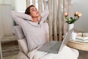 porträt einer jungen gestressten frau, die zu hause am schreibtisch vor dem laptop sitzt, den schmerzenden hals mit schmerzendem ausdruck berührt und nach der arbeit am pc unter nackenschmerzen leidet foto