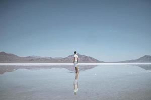 Reisende, die Bonneville Salt Flat und Bergkette betrachten, die sich im See widerspiegeln foto