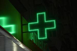 Grünes Kreuz Apotheken nachts in der Stadt. leuchtend mit led-lampen, das grüne kreuz des krankenhauses. foto