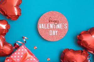 Happy Valentinstag Grußkarte. Podium oder Sockel und Geschenkbox mit roten Ballons in Herzform auf türkisfarbenem Hintergrund foto