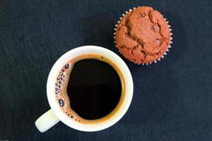 Tasse Kaffee und Cupcake auf dunklem Hintergrund foto