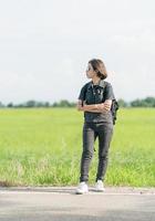 Frau mit Rucksack per Anhalter entlang einer Straße foto