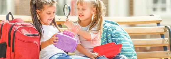 Grundschulkinder sitzen mit Lunchpaketen foto