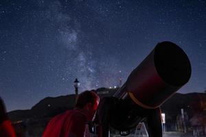 Mann, der durch das Teleskop auf das Griffith-Observatorium am Mount Hollywood blickt foto