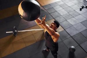 Basketball spielen. starker afroamerikanischer mann in sportlicher kleidung hat einen trainingstag im fitnessstudio foto