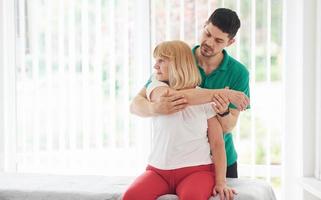 ältere frau hat einen besuch in der klinik und rehabilitierung. männlicher lehrer hilft ihr foto