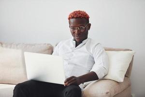 junger afroamerikanischer mann in formeller kleidung drinnen mit laptop in den händen foto