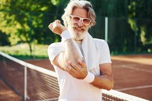 Schmerzgefühl aufgrund eines Traumas. Älterer, moderner, stilvoller Mann im Freien auf dem sportlichen Feld tagsüber foto