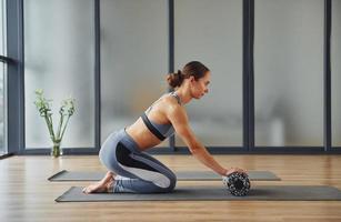 Übungen für die Wirbelsäule. junge frau in sportlicher kleidung und mit schlankem körper haben fitness-yoga-tag drinnen foto