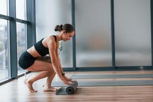 Übungen beginnen. junge frau in sportlicher kleidung und mit schlankem körper haben fitness-yoga-tag drinnen foto