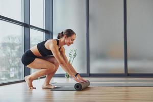 Übungen beginnen. junge frau in sportlicher kleidung und mit schlankem körper haben fitness-yoga-tag drinnen foto