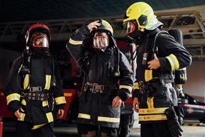Schutzuniform tragen. Gruppe von Feuerwehrleuten, die auf Station ist foto