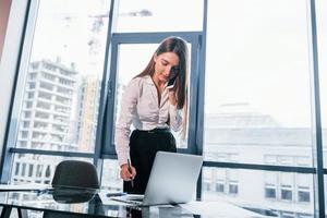 junge frau in weißer formeller kleidung ist drinnen im modernen büro foto