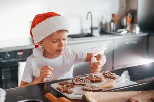 kleiner Junge bereitet Weihnachtsplätzchen in der Küche zu foto