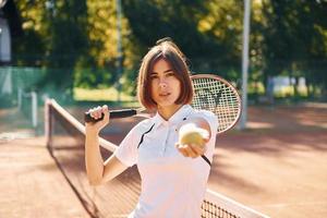 stehend mit Schläger in der Hand. Tennisspielerin ist tagsüber auf dem Platz foto