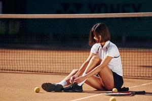 in weißem Hemd und schwarzem Rock. Tennisspielerin ist tagsüber auf dem Platz foto