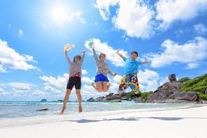 glückliche familie, die am strand in thailand springt foto