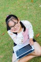 schönes Mädchen mit einem Laptop auf dem Rasen foto