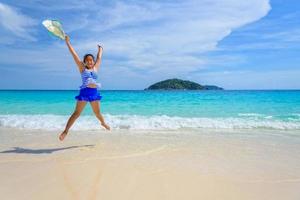 mädchen, das mit glücklichem auf dem strand in thailand springt foto