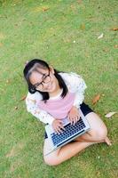 schönes Mädchen mit einem Laptop auf dem Rasen foto