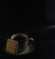 schwarzer Kaffee und Kekse auf dem schwarzen Hintergrund foto