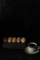 Kolombengi-Kuchen und eine Tasse Tee auf schwarzem Hintergrund isoliert. indonesischer Kuchen foto