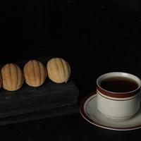 Kolombengi-Kuchen und eine Tasse Tee auf schwarzem Hintergrund isoliert. indonesischer Kuchen foto
