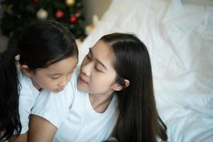 Die ältere Schwester sah ihre neugeborene kleine Schwester an, während sie schlief. im weißen Schlafzimmer foto