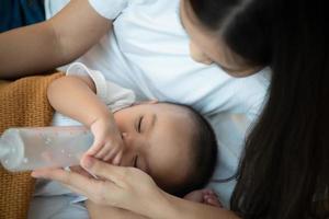 junge mutter umarmt ihr neugeborenes kind, um das baby in den schlaf zu wiegen, während sie milch trinkt foto