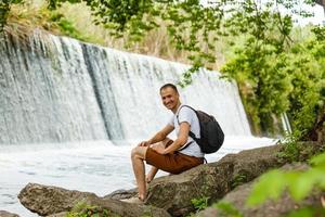 Rucksackgurt für Reisen auf der Schulter des touristischen Wasserfalls Hintergrund Nahaufnahme Wanderreise Travel Trek Konzept. foto