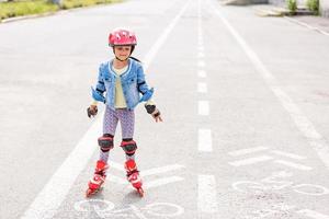 kleines Mädchen, das auf den Gleisen Rollerblades fährt foto