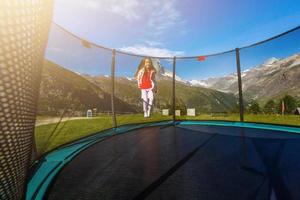 kleines Mädchen auf einem Trampolin in den Bergen, Alpen foto