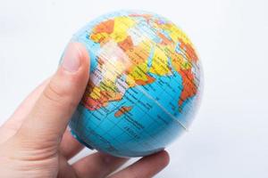 Hand, die ein Globusmodell auf weißem Hintergrund hält foto