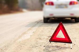 rotes Dreiecksschild und Auto auf der Straße, geringe Sichttiefe foto