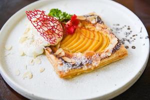 Pfirsichkuchen auf weißem Teller - hausgemachtes Dessert leckerer Kuchen mit Pfirsichen und Puderzucker foto