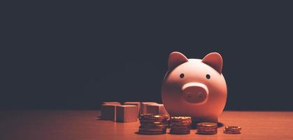 Geld sparen, Finanzplanung der persönlichen Finanzen und sparsames Konzeptthema mit einem rosa Sparschwein, das auf einem Holztisch sitzt. foto
