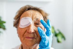 Nahaufnahme des verletzten Auges einer älteren Frau und der Finger der Krankenschwester foto